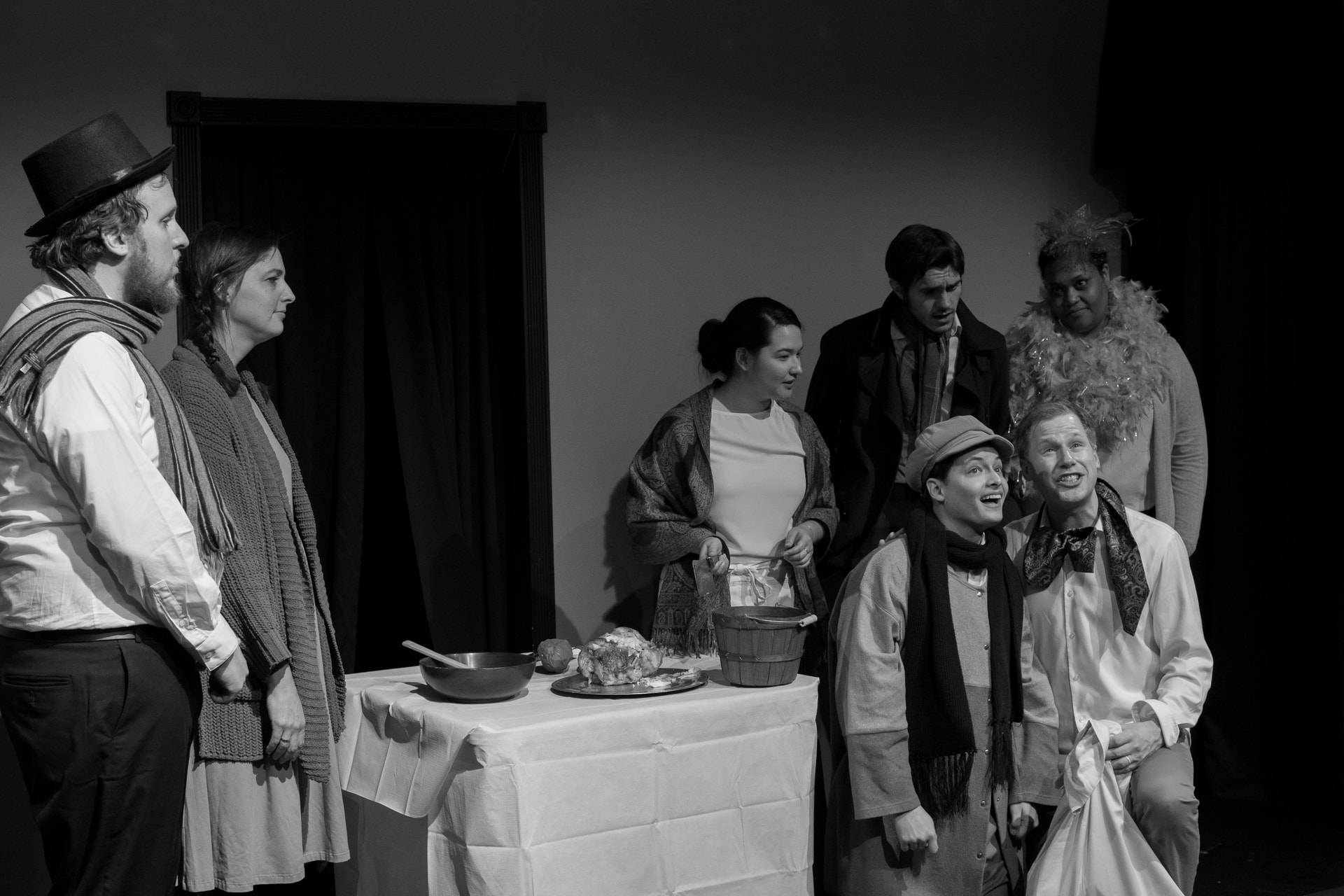A black and white photo befitting A Christmas Carol. But, BOO HUMBAG, something is amiss. There is a Young Dog (Actually a Human, Tiny Tim) informing Ebenezer Scrooge with gold teeth the true meaning of Christmas with family and friends looking on. There is chicken on the table. This chicken is real. Jerome would have to eat it every night. It is not what made him sick, we think, but he got so sick after the first night. We could not put our finger on what made him sick. It could not have possibly then the (cooked?) chicken just out and about for a few hours since this only came out at the end of the show and was in a dorm room grade quality fridge in a green room. Could not have been the chicken.