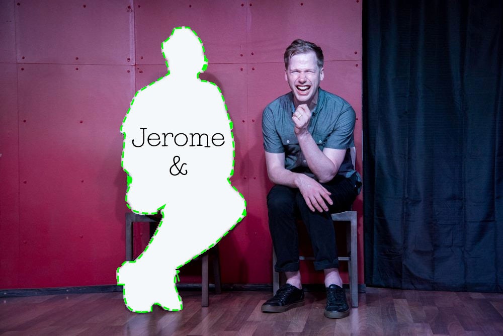 Jerome is sitting next to a seated silhouette of a person to their left. In the silhouette is “Jerome &.” Jerome is sitting in front of a red wall, with a black curtain to the right. He is cheesing something ridiculous with a giant smile, closed eyes, and his arms draped over his legs. It is obvious something funny just happened, but what could it have been?!